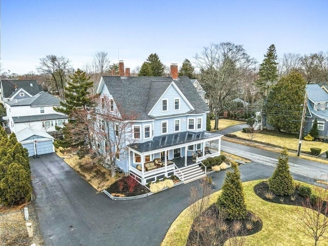 rear view of house featuring a porch, a garage, and a chimney