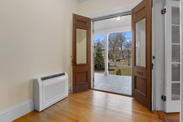 foyer with heating unit, baseboards, and light wood finished floors