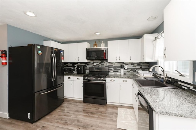 kitchen with sink, dark stone counters, white cabinets, and appliances with stainless steel finishes