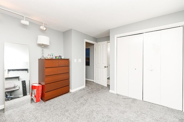 bedroom with rail lighting, light colored carpet, and a closet