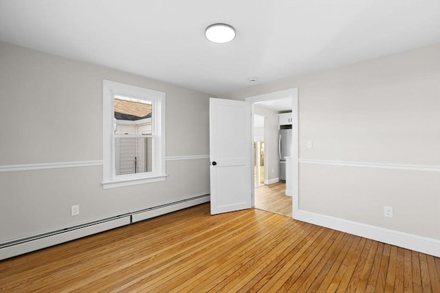 empty room with light hardwood / wood-style flooring and a baseboard radiator