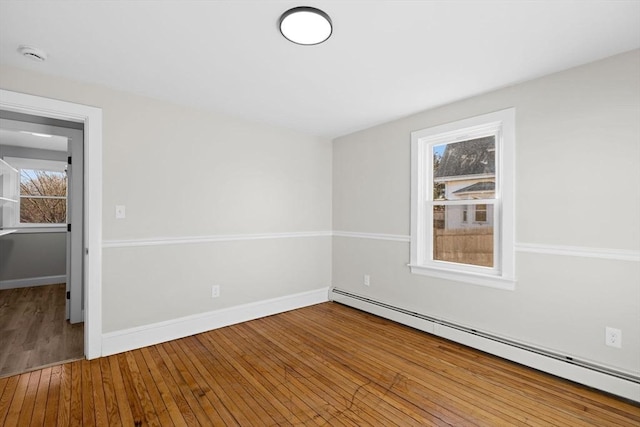 empty room featuring hardwood / wood-style flooring and a baseboard heating unit