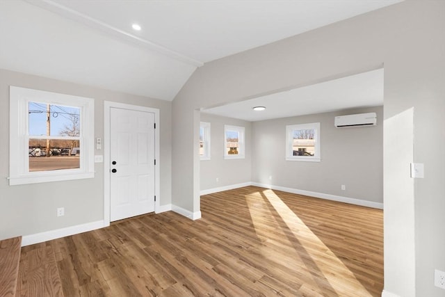 foyer with wood-type flooring, lofted ceiling, and a wall mounted air conditioner