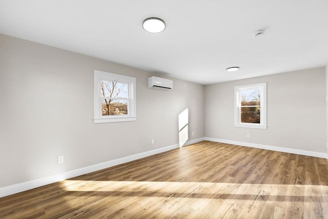 unfurnished room with a wealth of natural light, light hardwood / wood-style floors, and an AC wall unit