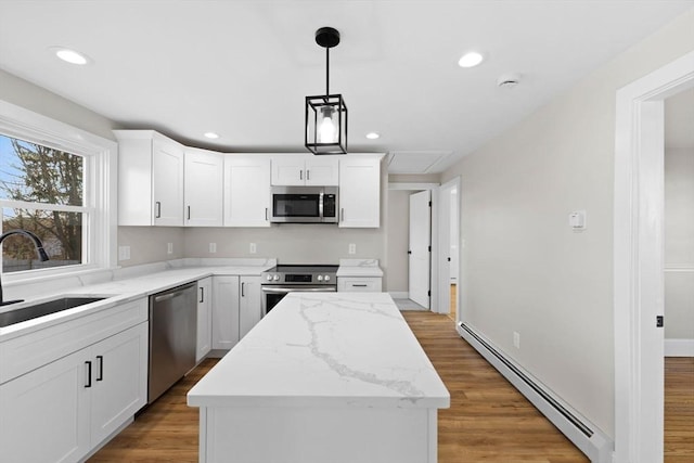 kitchen with a kitchen island, appliances with stainless steel finishes, white cabinetry, sink, and baseboard heating