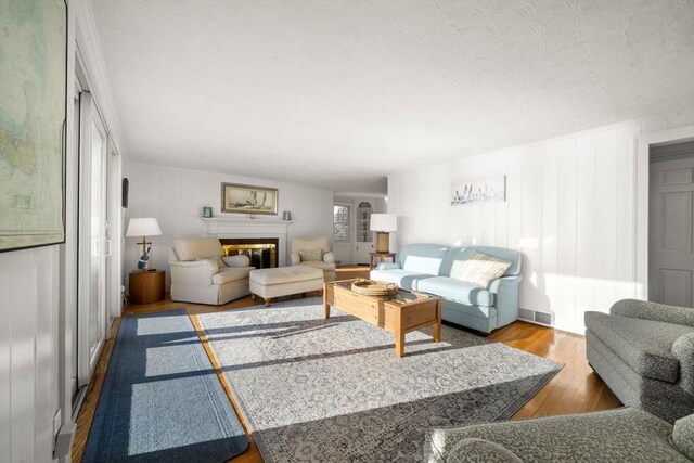 30 Captain Nickerson Ln, Dennis, MA 02660 - living area with a glass covered fireplace, wood finished floors, a textured ceiling, and visible vents