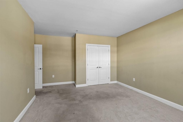 unfurnished bedroom featuring light carpet, a closet, and baseboards