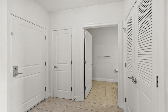 hall featuring light tile patterned floors and baseboards