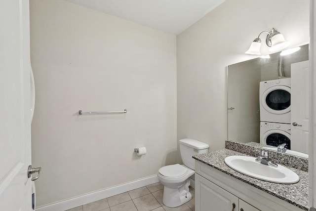 half bath featuring stacked washer and clothes dryer, toilet, vanity, tile patterned flooring, and baseboards