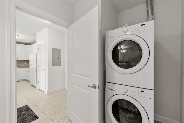 laundry area featuring light tile patterned floors, laundry area, stacked washer / dryer, baseboards, and electric panel