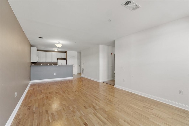 unfurnished living room featuring light wood-style floors, baseboards, and visible vents