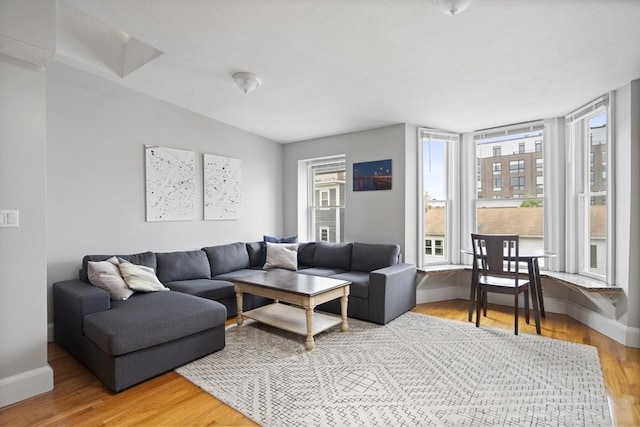 living area featuring healthy amount of natural light, baseboards, and light wood finished floors