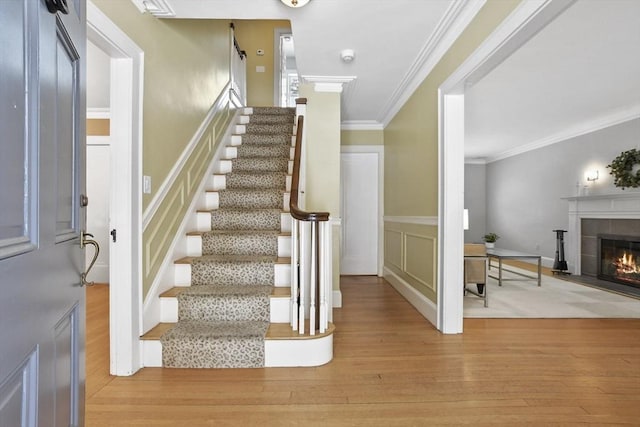 stairs featuring hardwood / wood-style flooring, crown molding, and a tiled fireplace