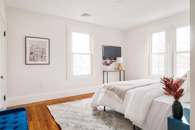 bedroom featuring wood finished floors, visible vents, and baseboards