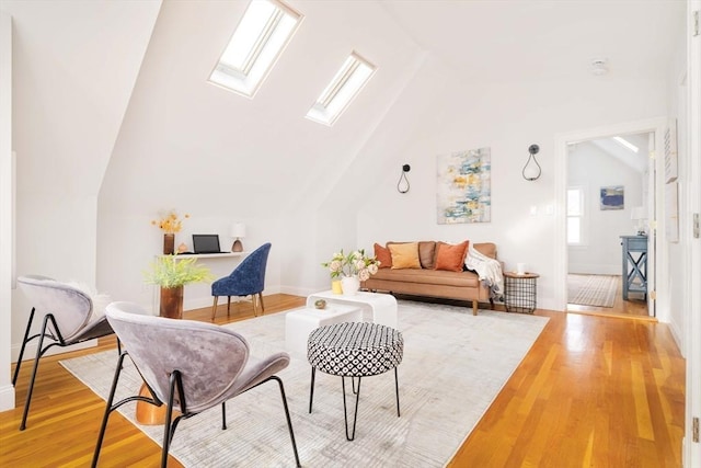 interior space with vaulted ceiling with skylight, baseboards, and light wood finished floors