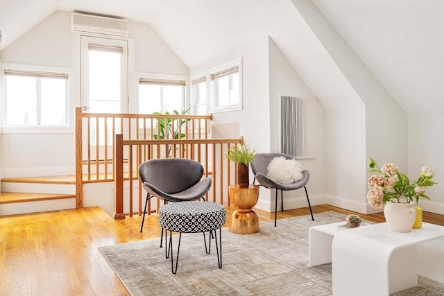 sitting room featuring lofted ceiling, wood finished floors, and a wall mounted AC