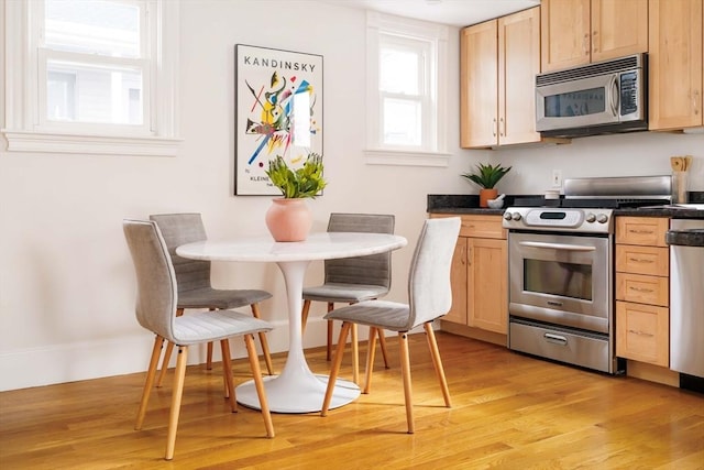 kitchen featuring dark countertops, light wood-style flooring, light brown cabinets, and stainless steel appliances