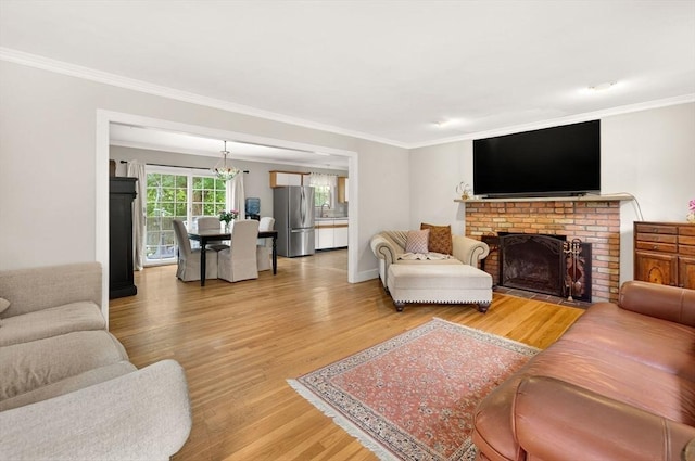 9 Arrowhead Ln, Dartmouth, MA 02748 - living area with ornamental molding, light wood-style flooring, a brick fireplace, and a chandelier