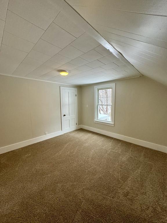 additional living space with vaulted ceiling and carpet floors