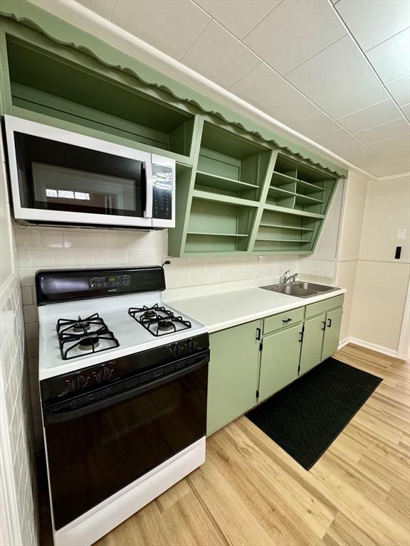 kitchen featuring green cabinetry, sink, gas range oven, and light hardwood / wood-style floors