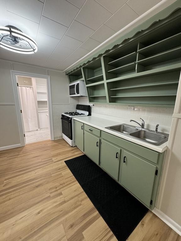 kitchen featuring gas stove, green cabinetry, sink, and light hardwood / wood-style flooring