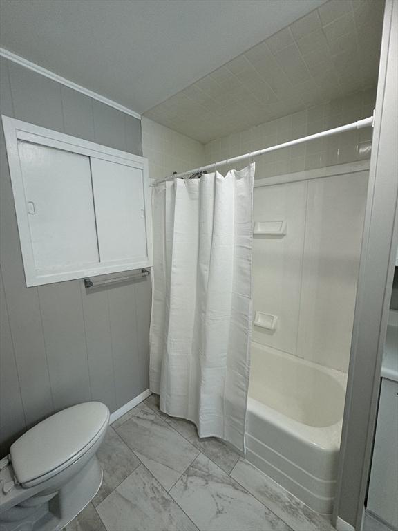 bathroom featuring shower / tub combo with curtain and toilet