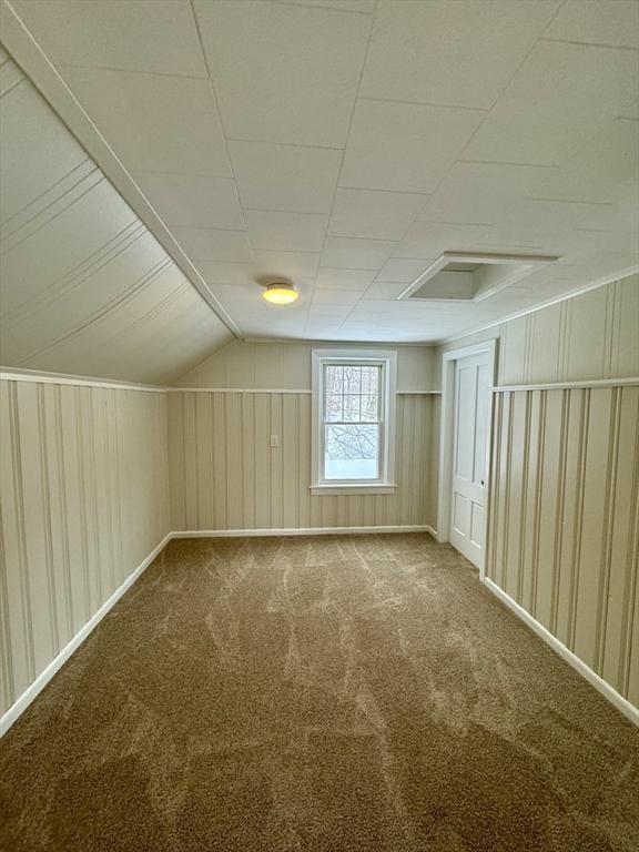 additional living space featuring lofted ceiling, carpet floors, and wooden walls