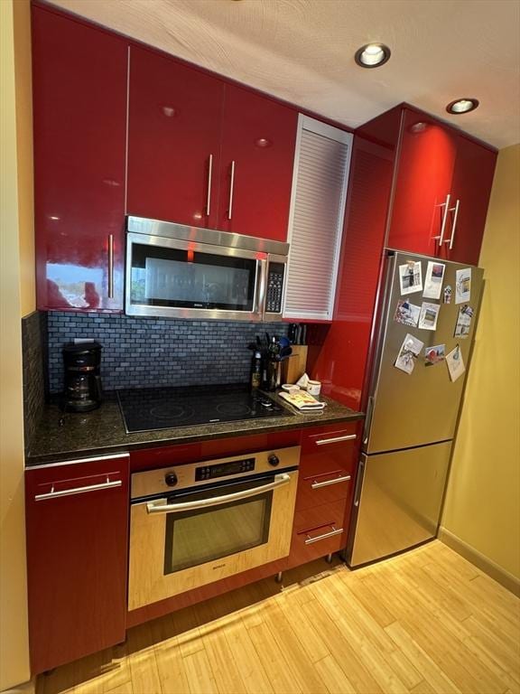 133 Commander Shea Blvd Unit 614, Quincy, MA 02171 - kitchen with appliances with stainless steel finishes, red cabinets, dark countertops, light wood finished floors, and recessed lighting