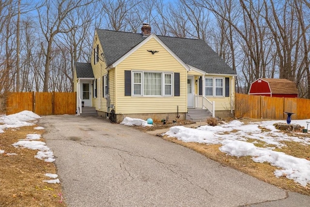 view of front of property with roof with shingles, a chimney, entry steps, fence, and driveway