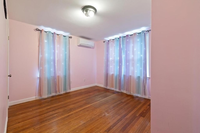 unfurnished room featuring a wall mounted air conditioner, wood finished floors, and baseboards