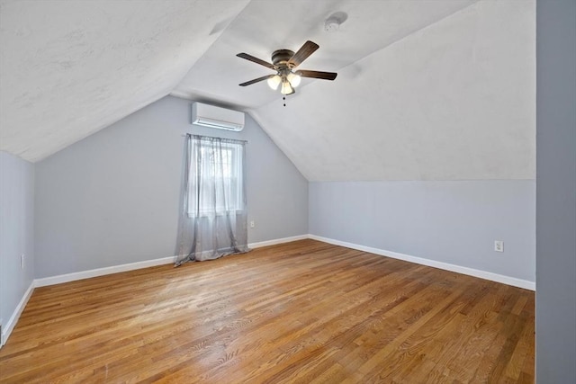 additional living space with baseboards, wood finished floors, and a wall mounted AC