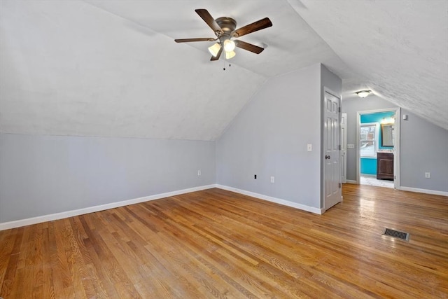 bonus room with a ceiling fan, baseboards, vaulted ceiling, visible vents, and light wood-style floors