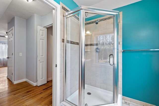 full bathroom with a shower stall, baseboards, and wood finished floors