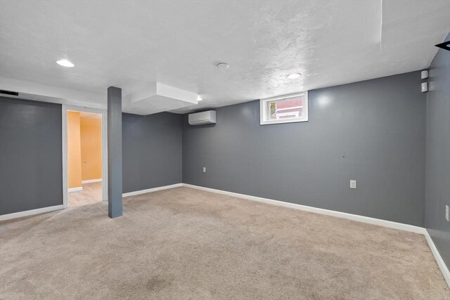 basement featuring carpet, a wall unit AC, and baseboards