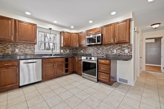 kitchen featuring stainless steel appliances, a sink, visible vents, a wall mounted AC, and brown cabinetry