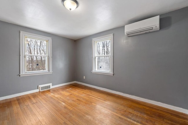 unfurnished room with plenty of natural light, baseboards, visible vents, and a wall mounted air conditioner