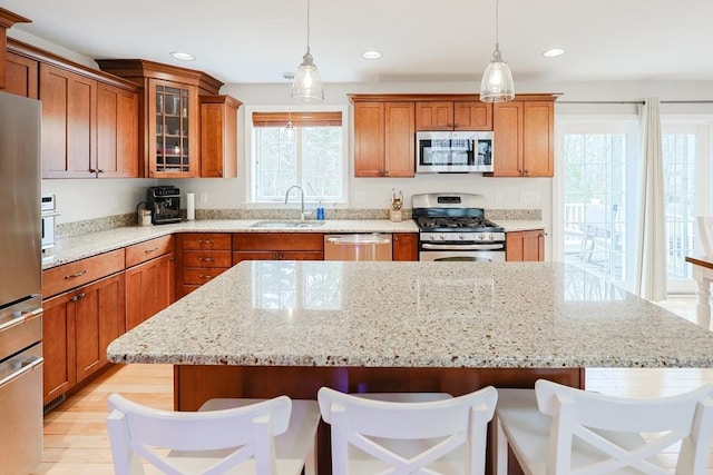 kitchen featuring a center island, stainless steel appliances, brown cabinetry, and a sink