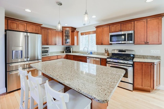 kitchen featuring a sink, stainless steel appliances, recessed lighting, light wood finished floors, and brown cabinetry