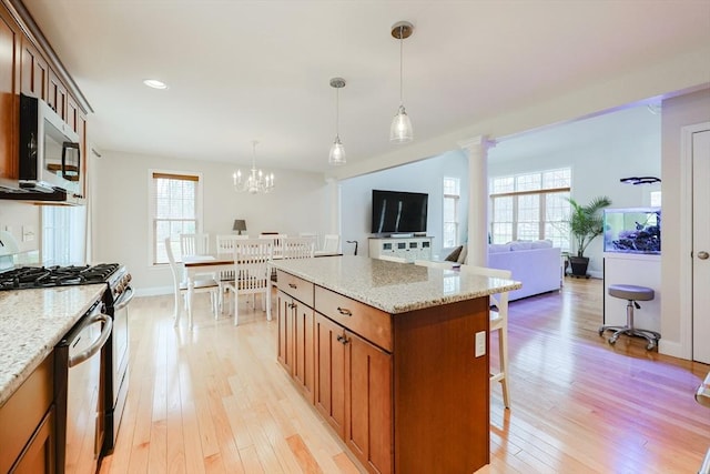 kitchen featuring a kitchen breakfast bar, light wood-style flooring, appliances with stainless steel finishes, a healthy amount of sunlight, and brown cabinetry