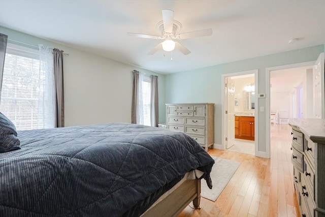 bedroom featuring baseboards, ceiling fan, light wood-style floors, and connected bathroom