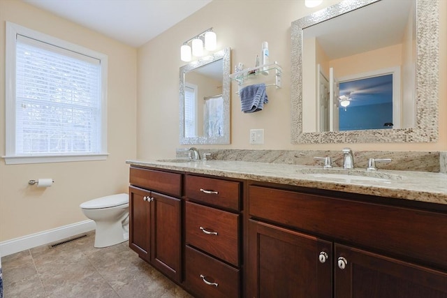 bathroom with baseboards, visible vents, toilet, and a sink