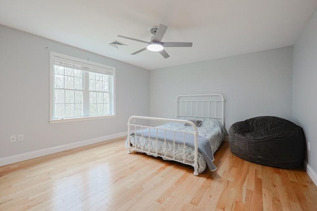 bedroom featuring baseboards, visible vents, wood finished floors, and a ceiling fan