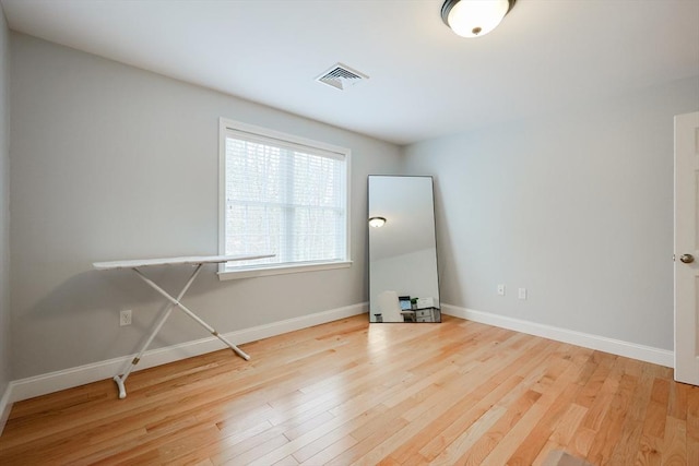 spare room featuring wood finished floors, visible vents, and baseboards