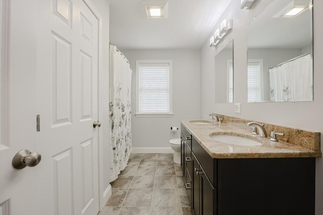 full bath featuring double vanity, a sink, and a healthy amount of sunlight