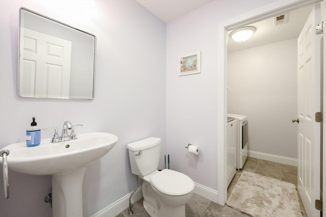 bathroom featuring visible vents, toilet, washing machine and clothes dryer, and baseboards