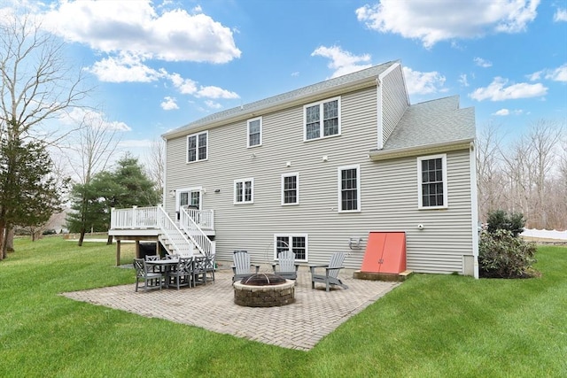 back of house featuring a patio, a wooden deck, a yard, and a fire pit