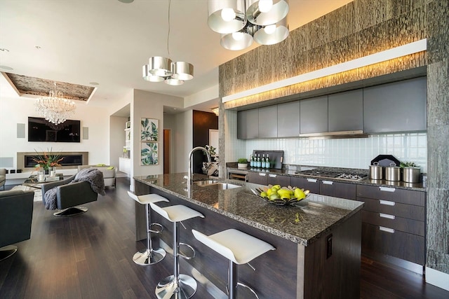 kitchen with backsplash, an inviting chandelier, dark hardwood / wood-style flooring, sink, and a kitchen breakfast bar