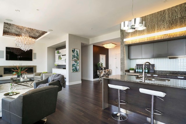 kitchen with dark stone countertops, pendant lighting, tasteful backsplash, an inviting chandelier, and a breakfast bar area