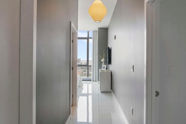 hallway featuring a wall of windows, a wealth of natural light, and light tile patterned floors