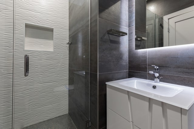 bathroom featuring a shower with shower door, vanity, and tile walls